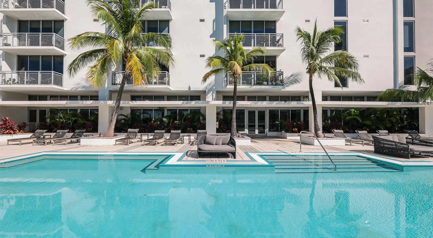 Amplia terraza de piscina con cómodos espacios para descansar